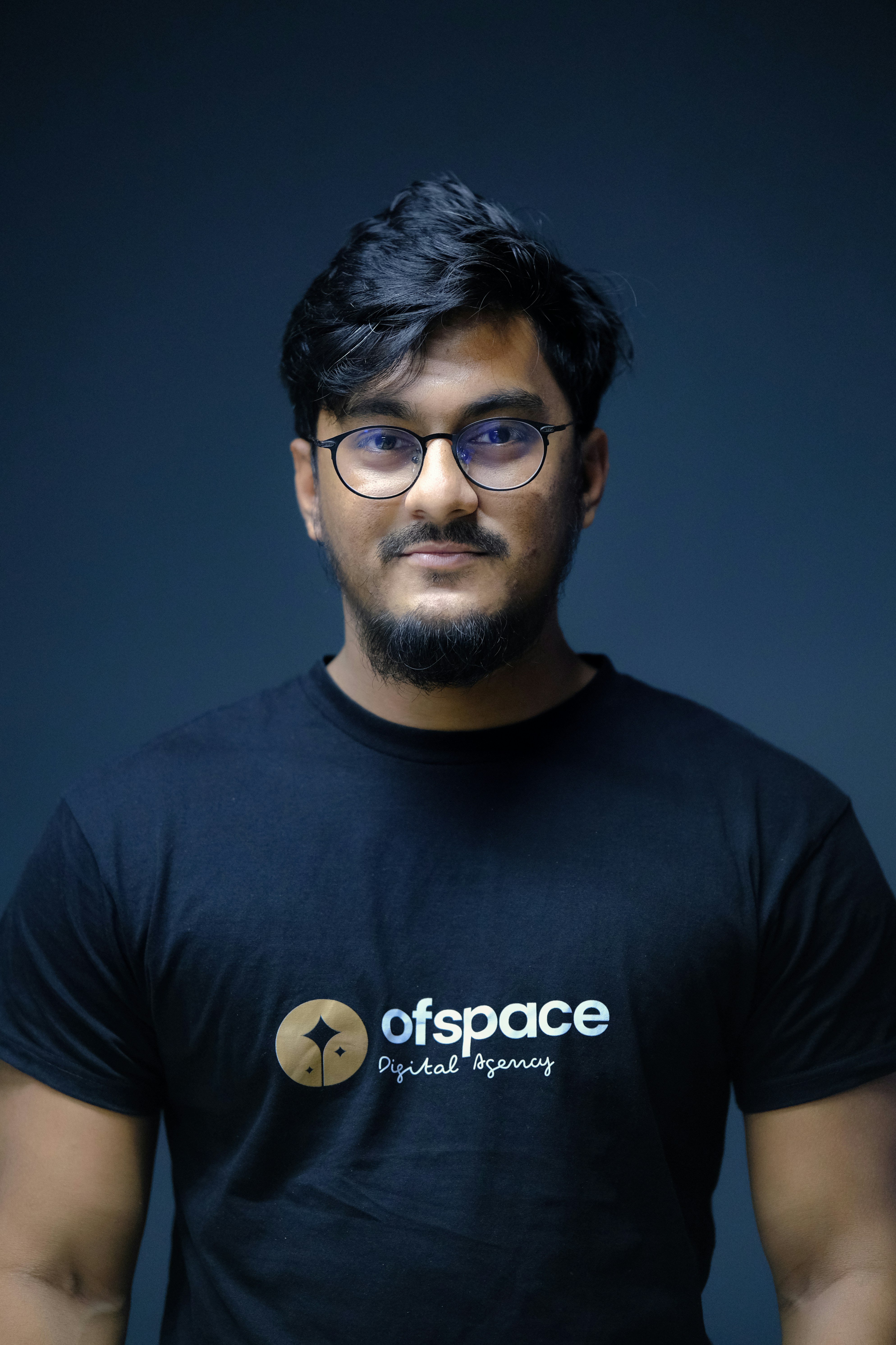 Man with glasses smiling confidently against light background