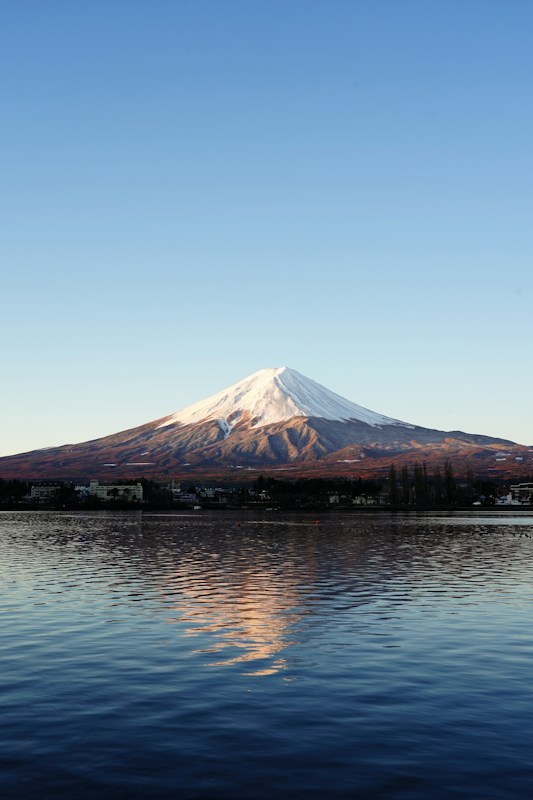 A still lake at dawn perfectly reflecting a snow-capped peak