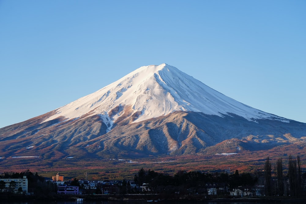 a large snow covered mountain towering over a city