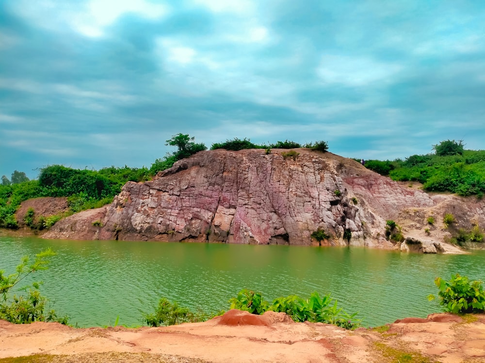 a large rock sitting on top of a lush green hillside