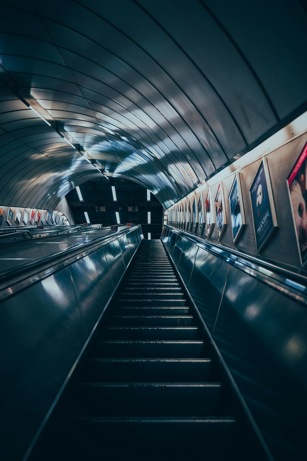 an escalator in a subway station with pictures on the wall