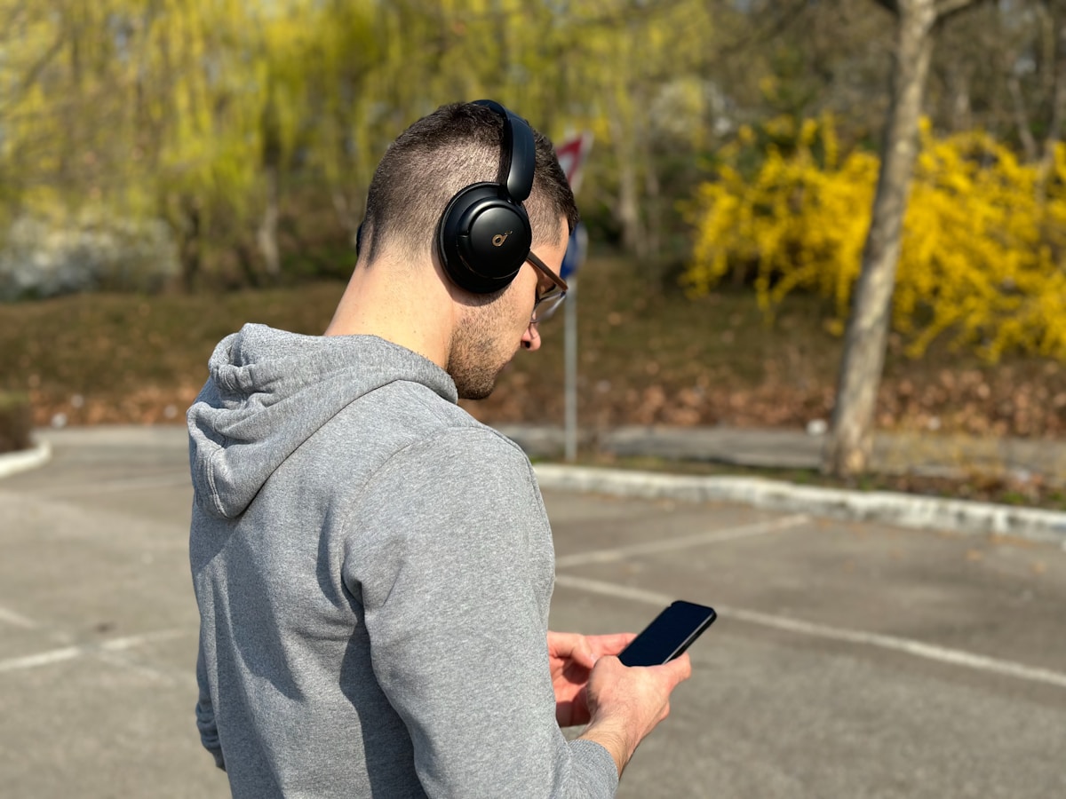 A man wearing headphones and looking at his cell phone