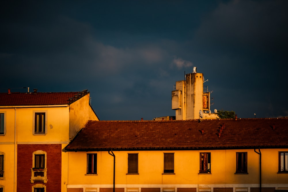 a yellow building with a red roof under a dark sky