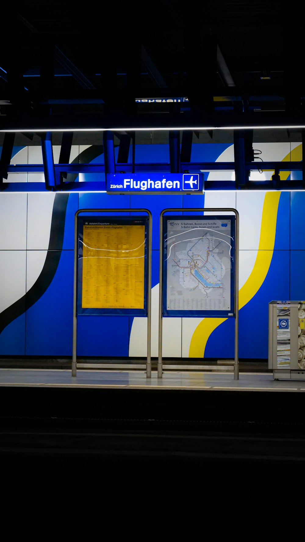 a train station with a blue and yellow wall