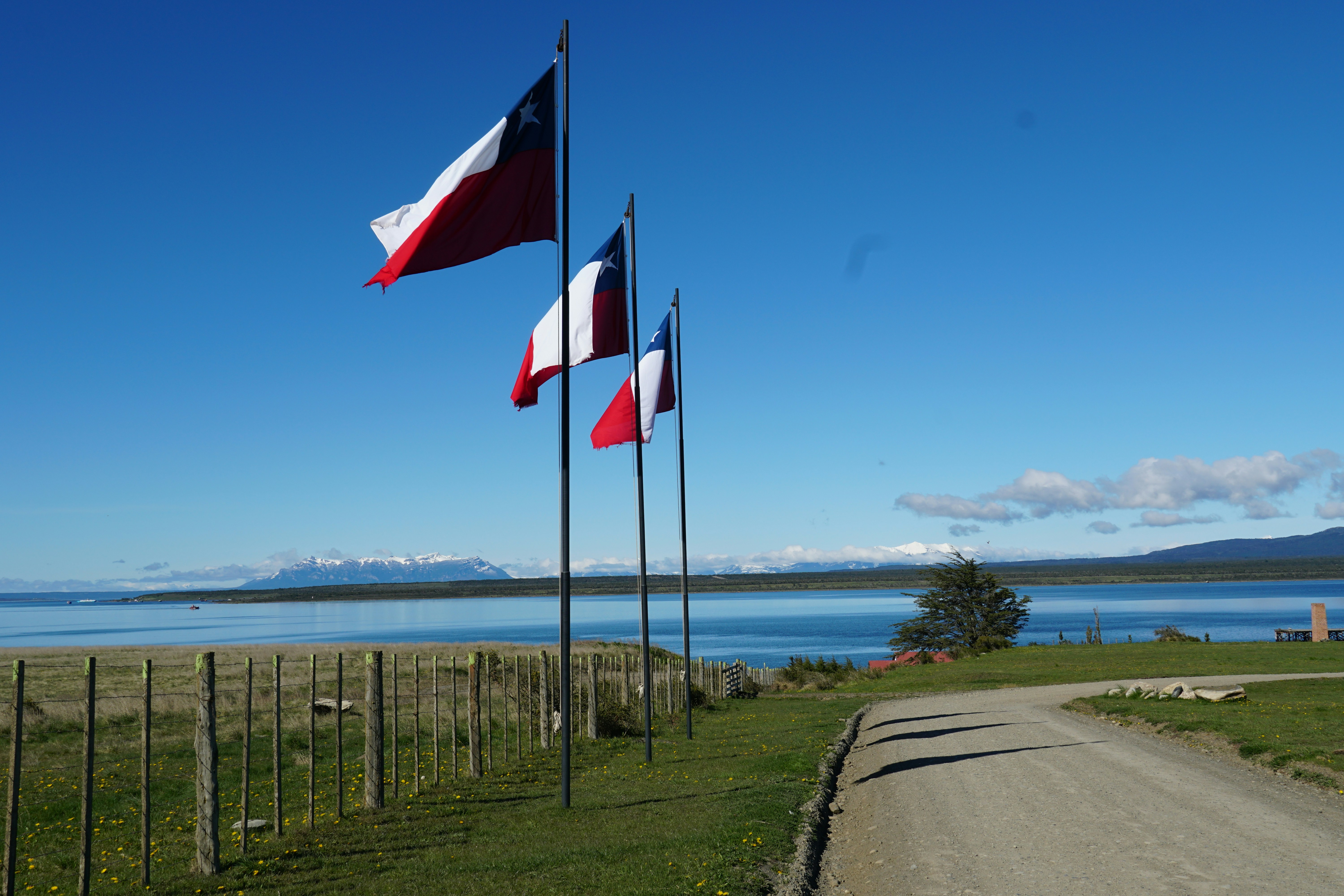 Tres banderas ondean en el viento cerca del agua