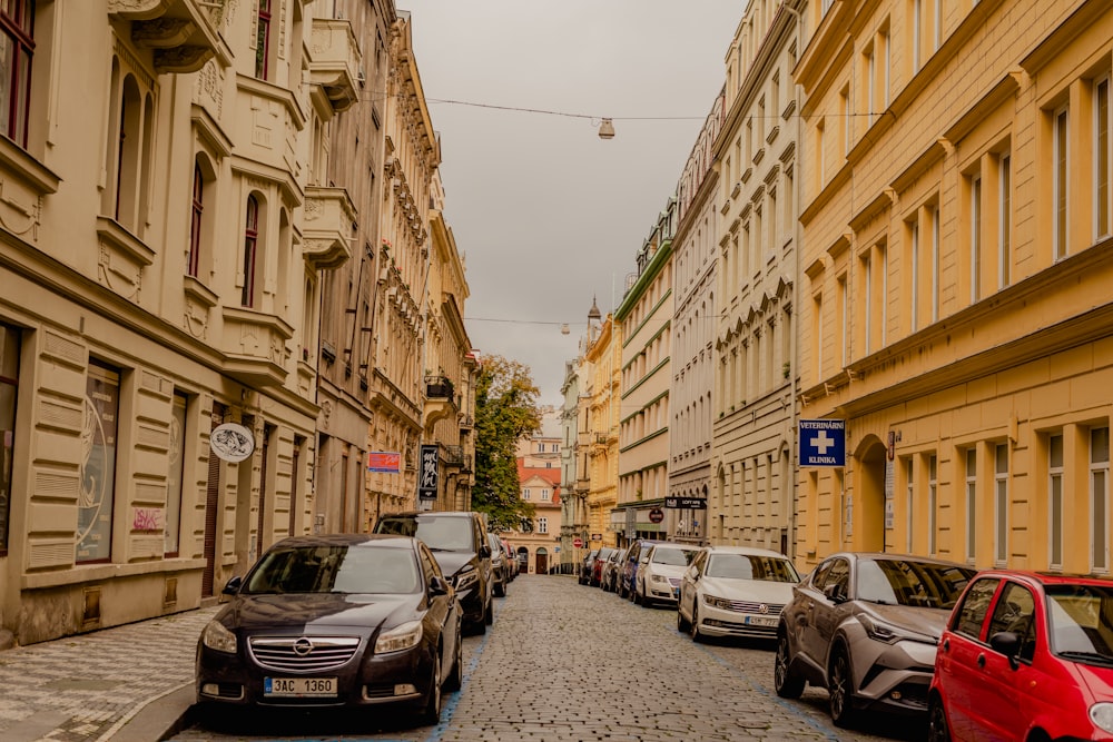 a city street lined with parked cars next to tall buildings