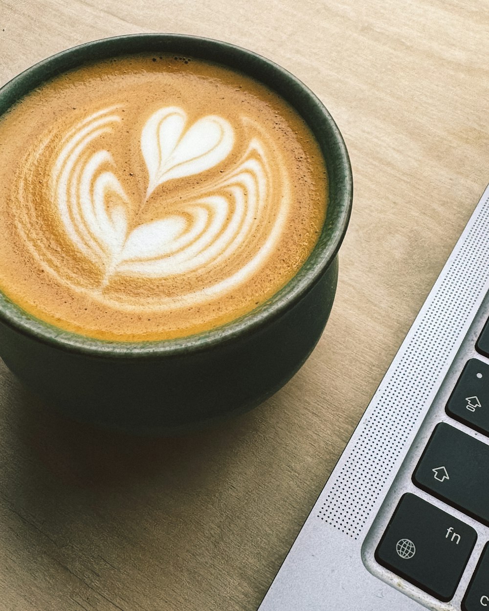 a cup of coffee sitting next to a laptop computer