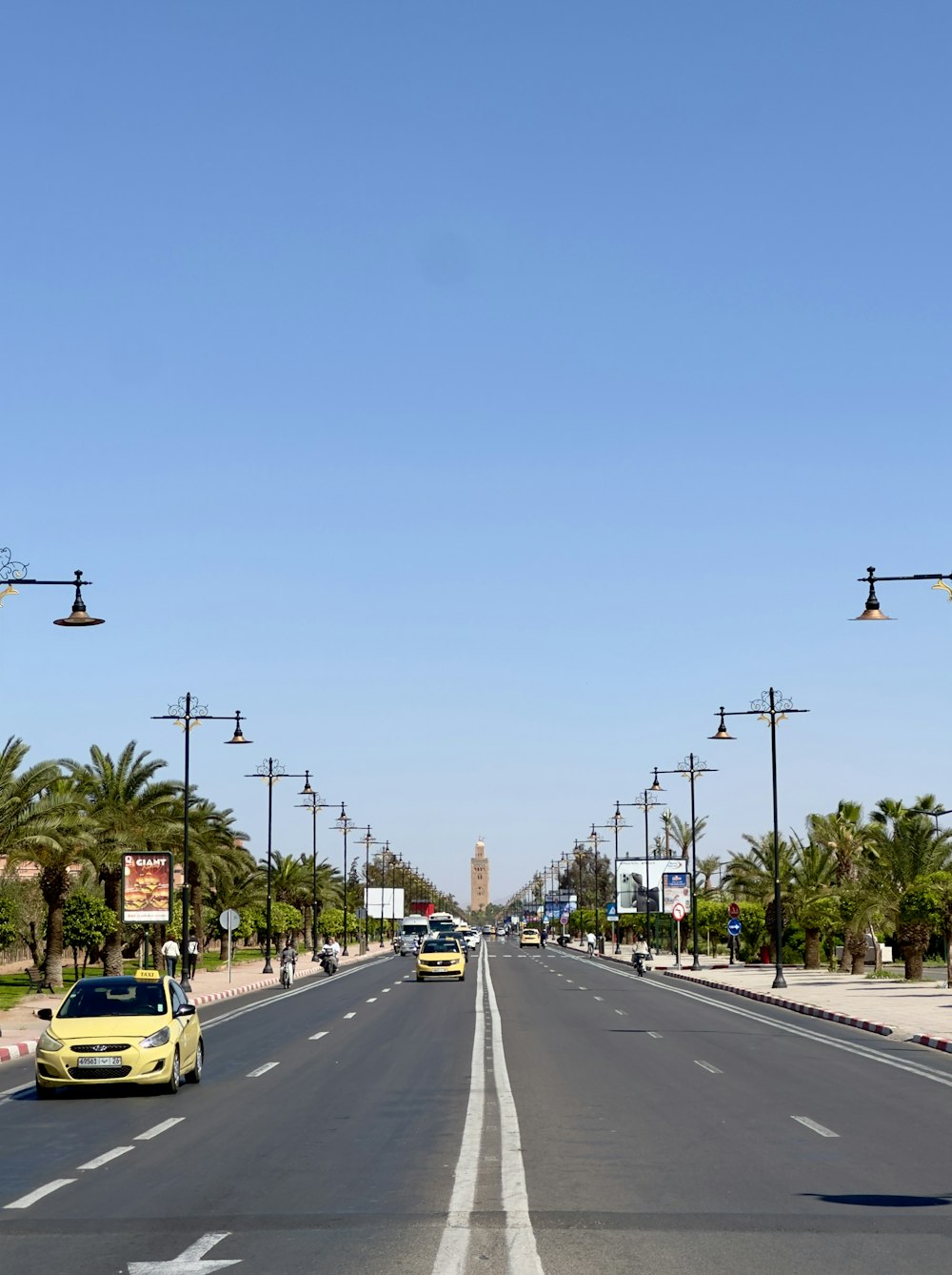 a yellow car driving down a street next to palm trees