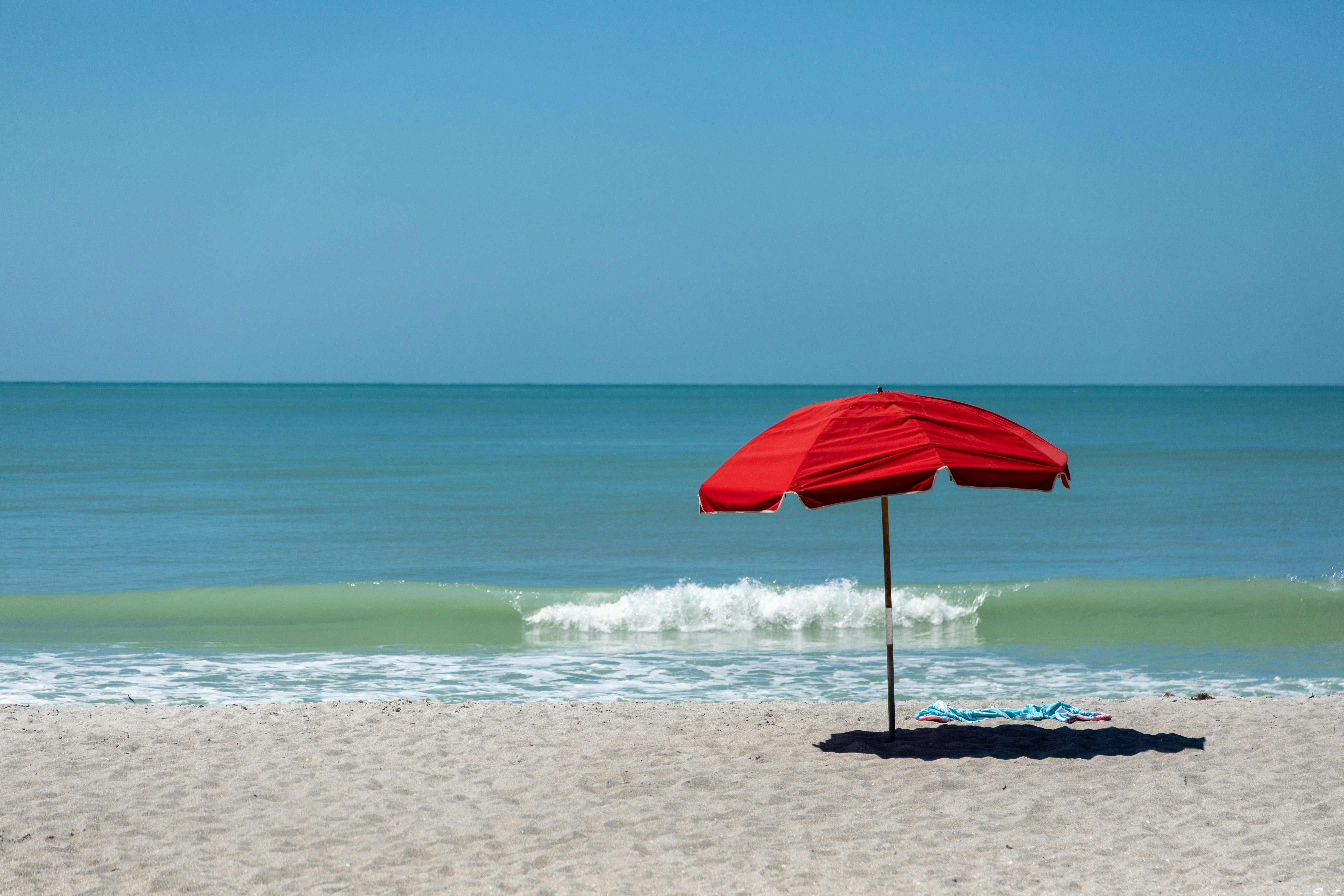 Um guarda-chuva vermelho sentado em cima de uma praia de areia foto –  Imagem grátis sobre Praia na Unsplash, image size:3000x2000