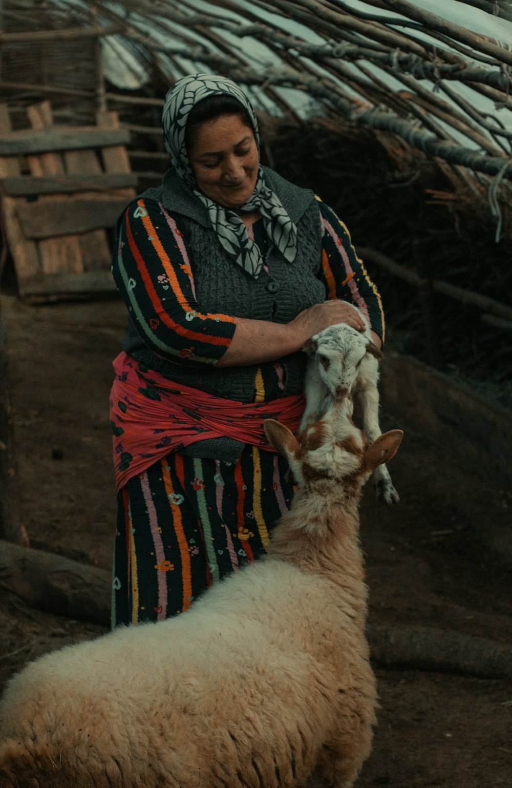 a woman holding a baby goat in her arms