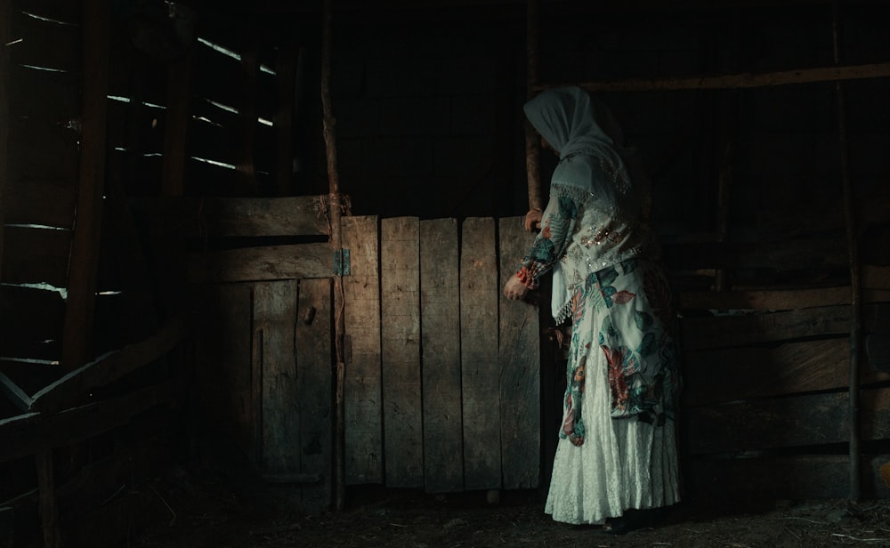 a woman in a white dress standing in a barn