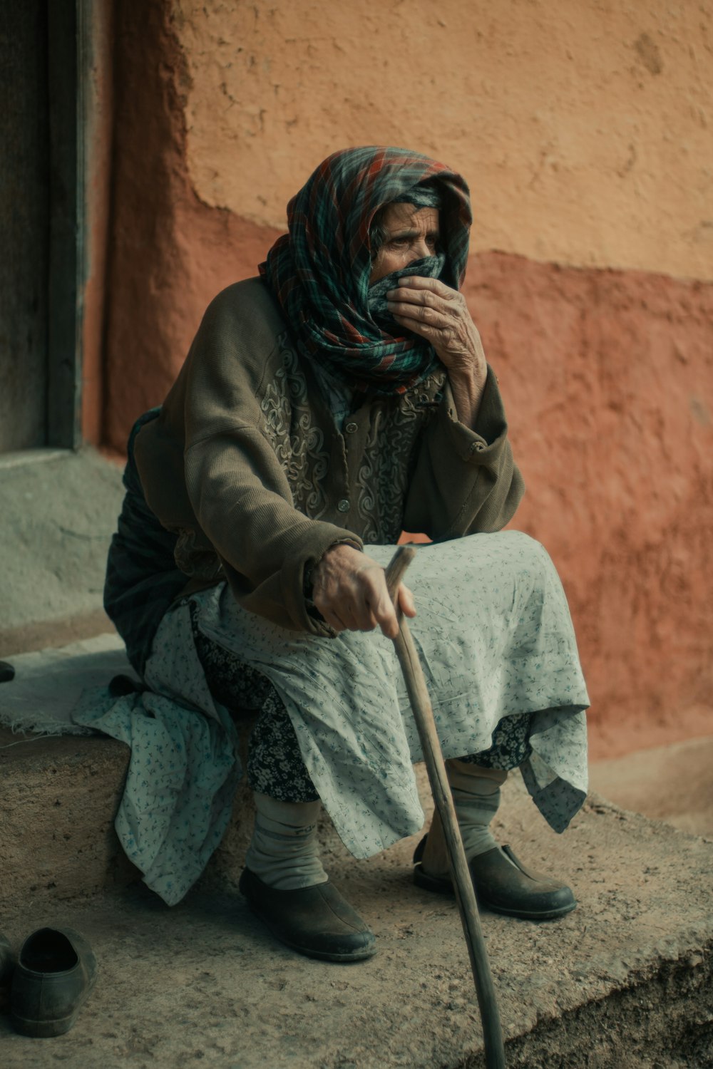 a woman sitting on a step with a cane