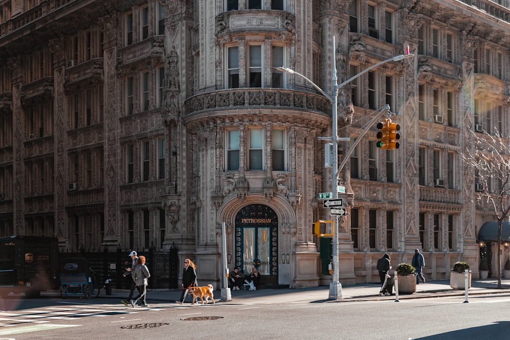 a group of people walking across a street next to a tall building