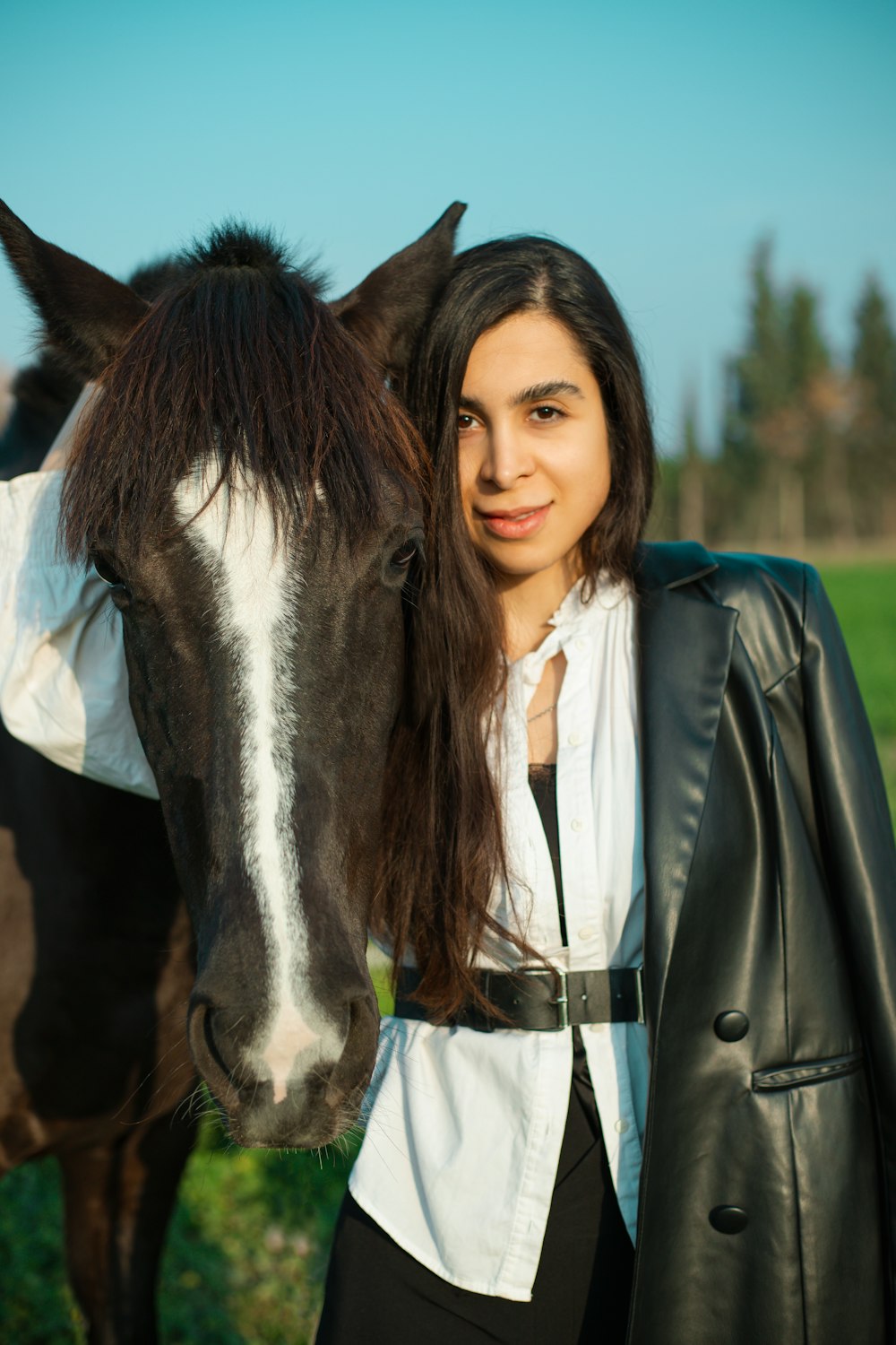 a woman standing next to a horse in a field