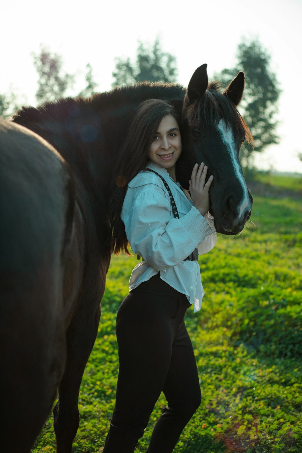a woman standing next to a horse in a field