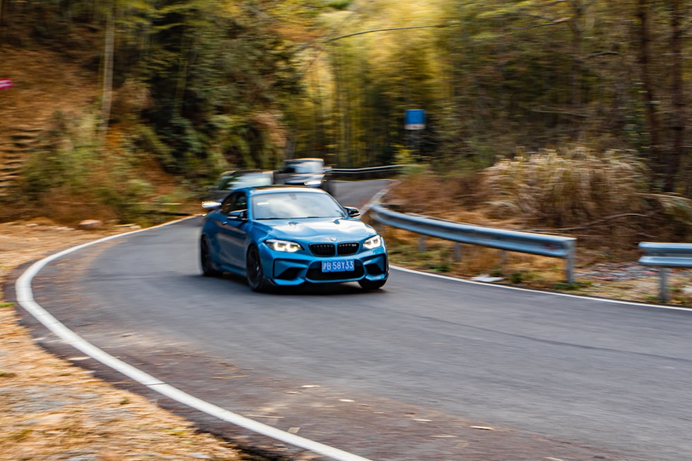 a blue car driving down a winding road