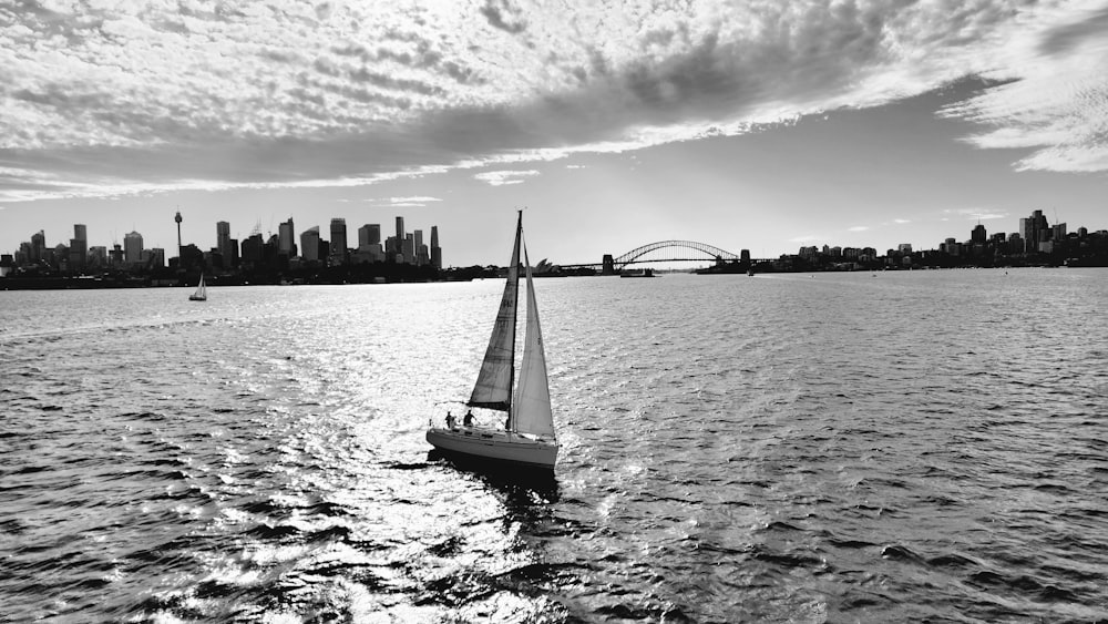 a sailboat in the water with a city in the background