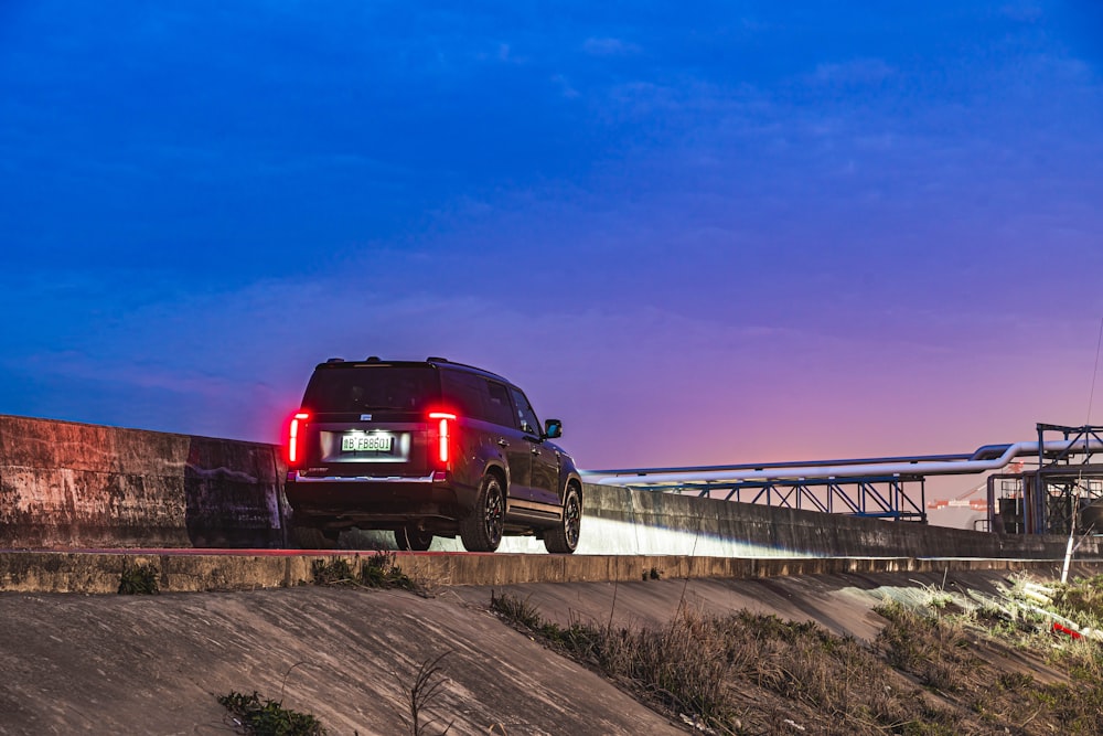 a black jeep driving down a road next to a bridge