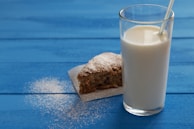 a glass of milk next to a piece of cake