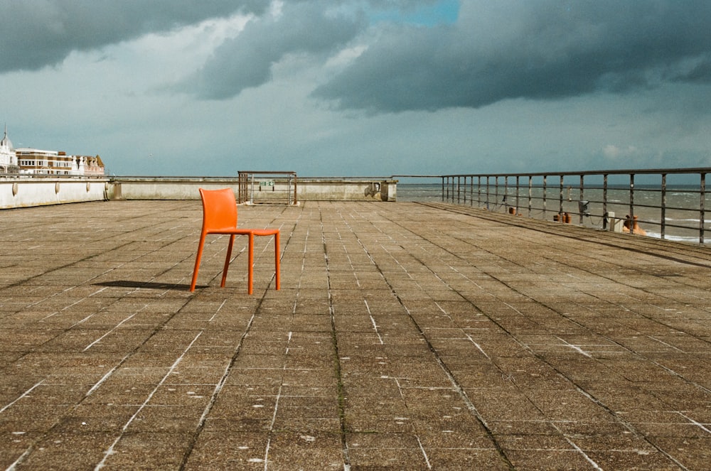 an orange chair sitting on top of a wooden pier