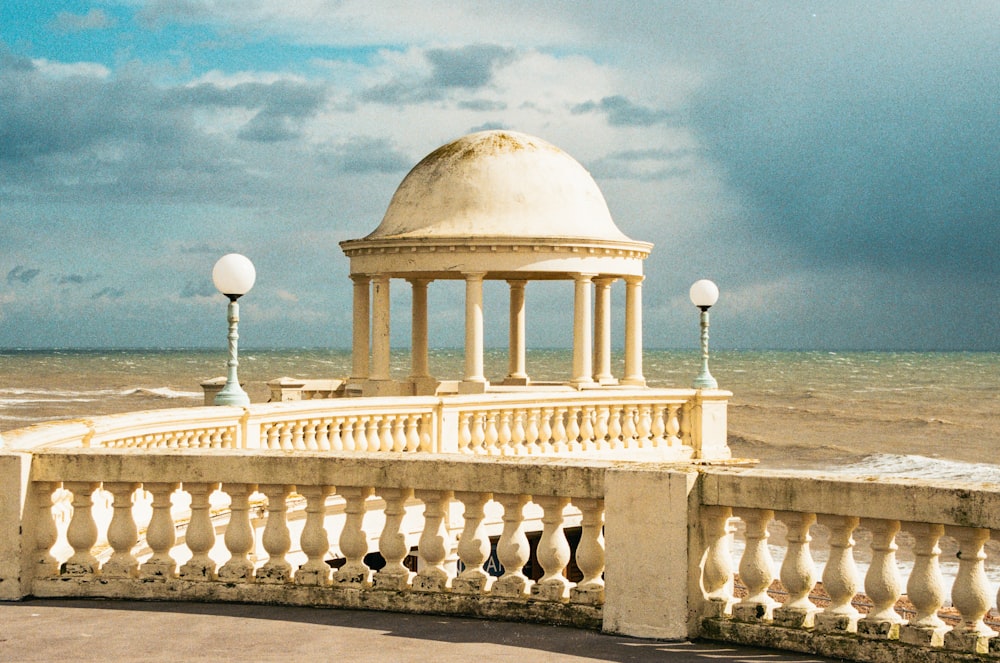 a gazebo sitting on top of a cement wall next to the ocean