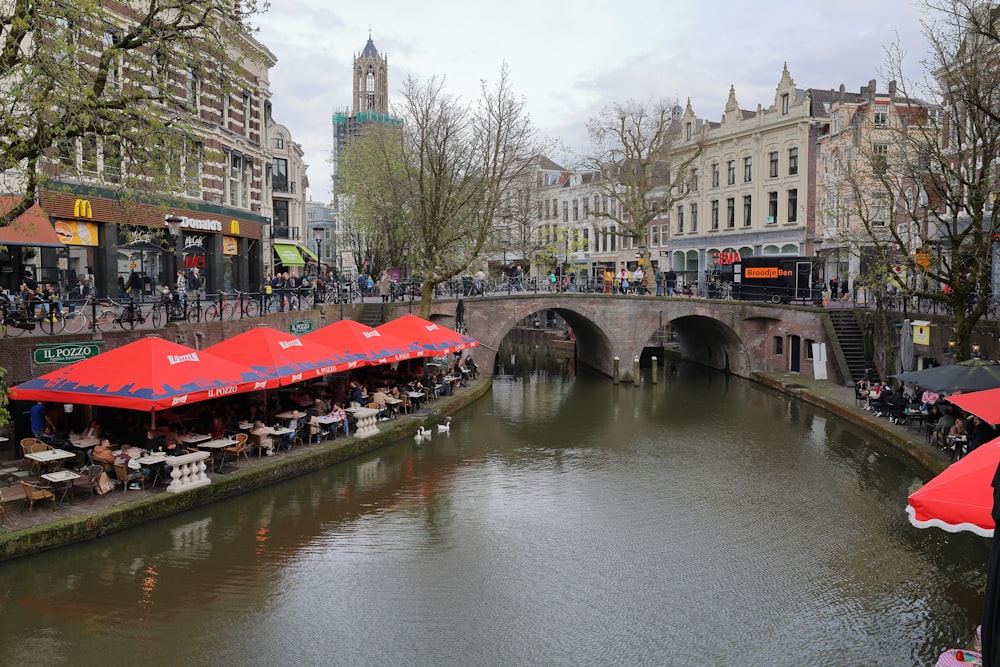 a river running through a city with lots of tables and umbrellas