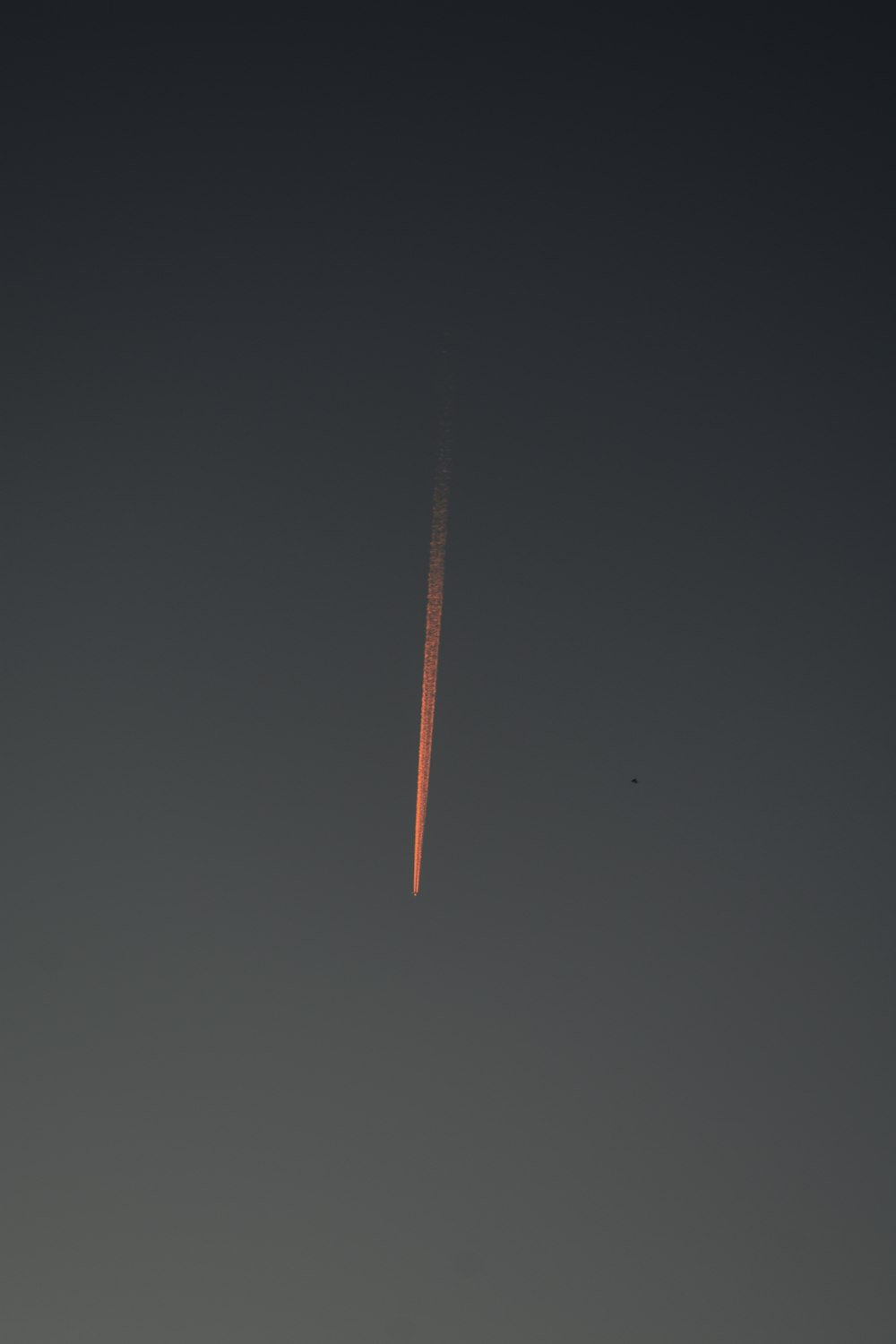 an airplane flying in the sky with a contrail in the background