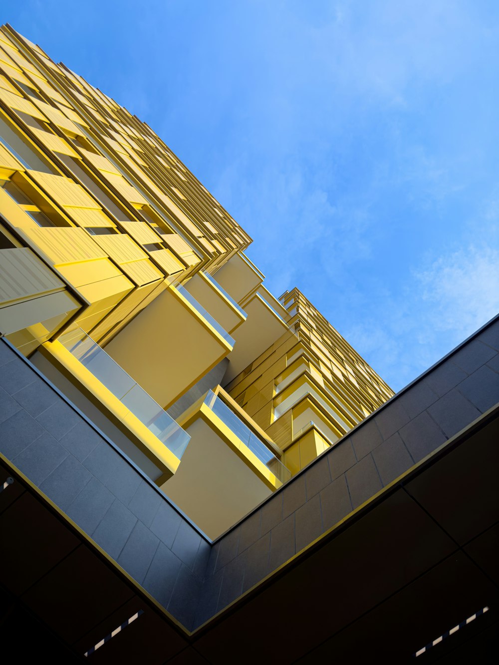 a tall yellow building with a blue sky in the background