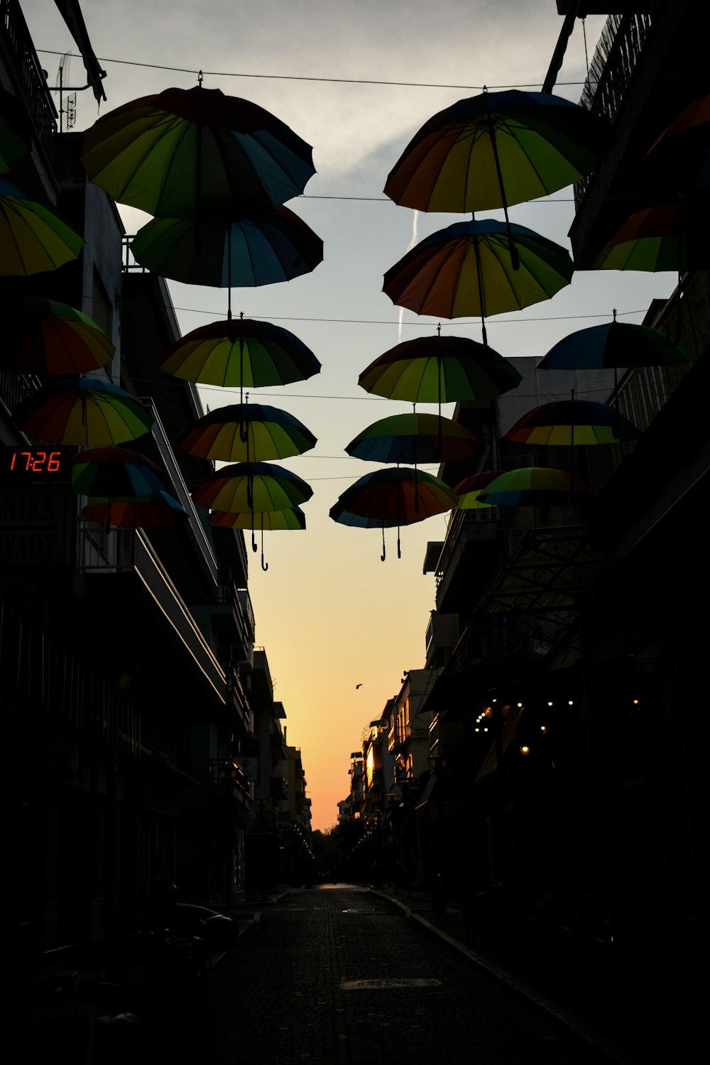 a street lined with umbrellas hanging from the side of buildings