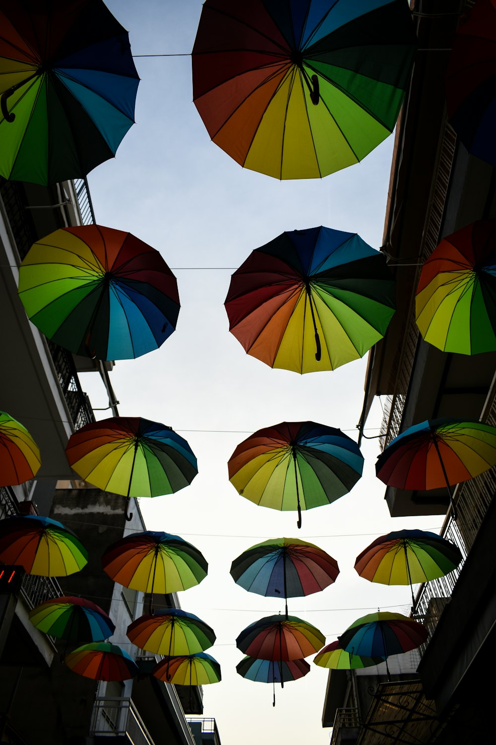 a group of multicolored umbrellas hanging from a building