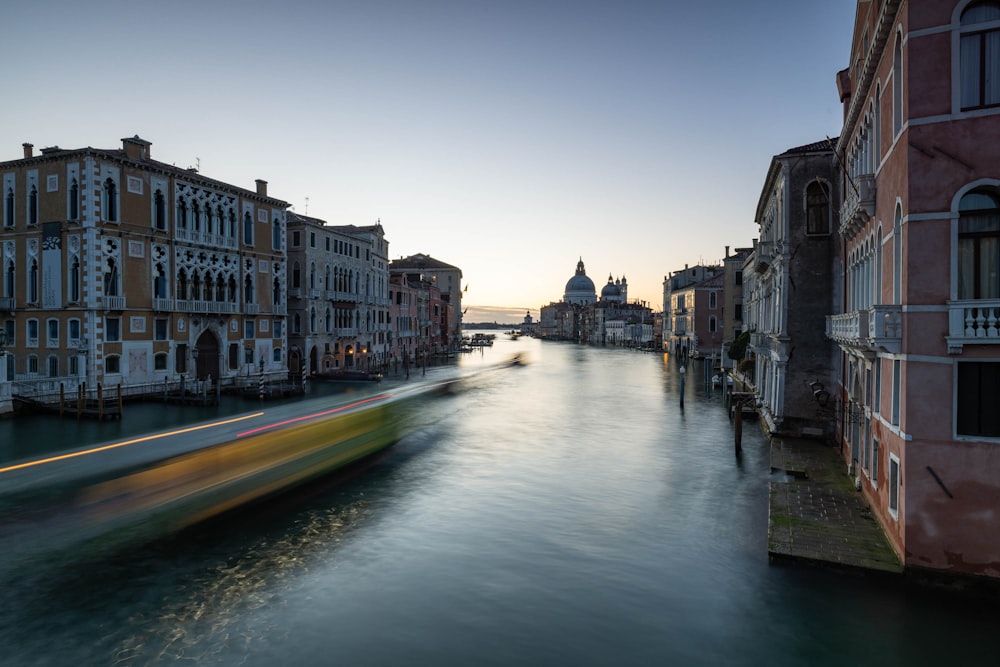 a boat traveling down a river next to tall buildings