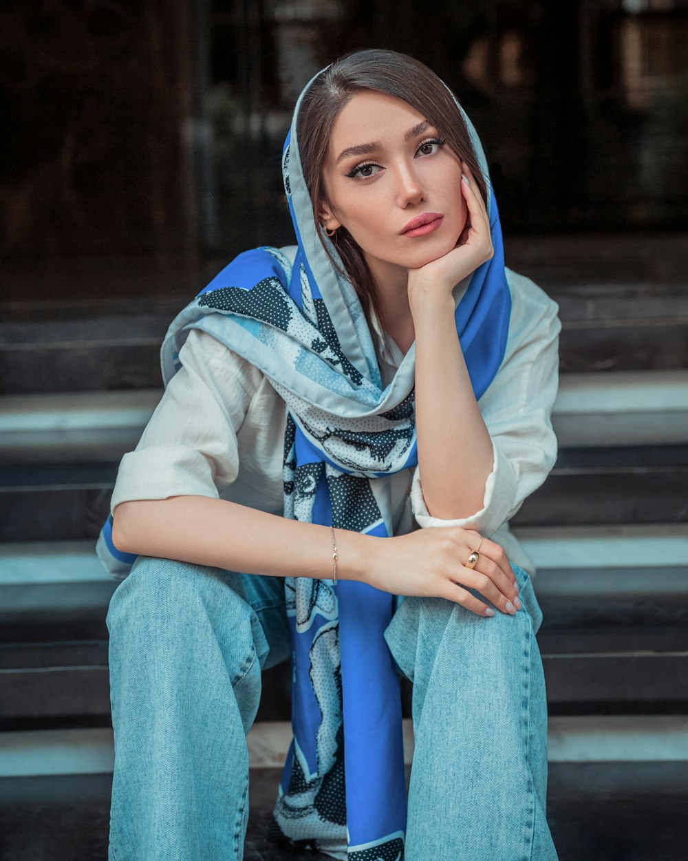 a woman sitting on a step wearing a blue scarf
