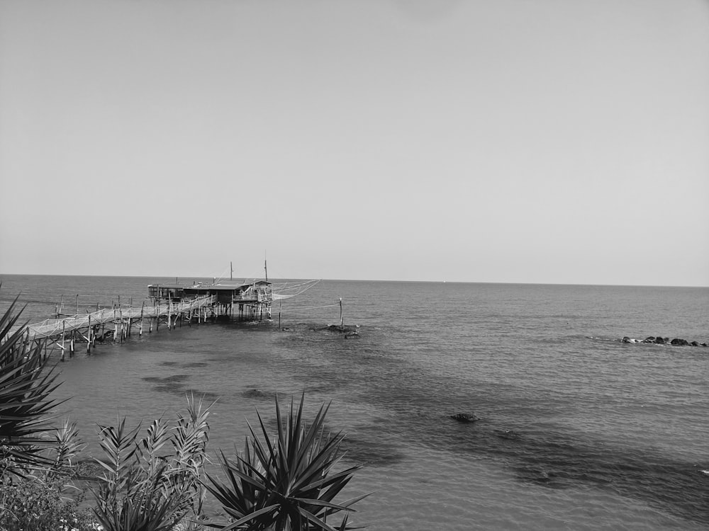 a black and white photo of a pier in the ocean