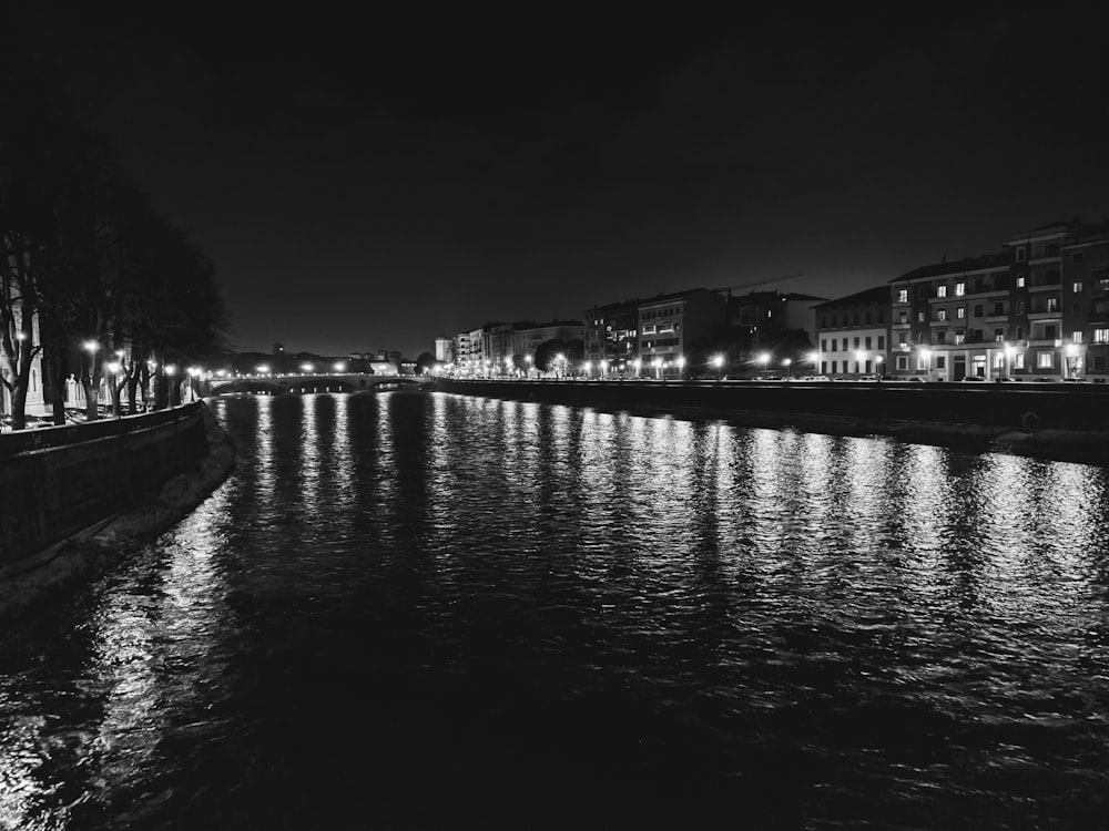 a black and white photo of a river at night