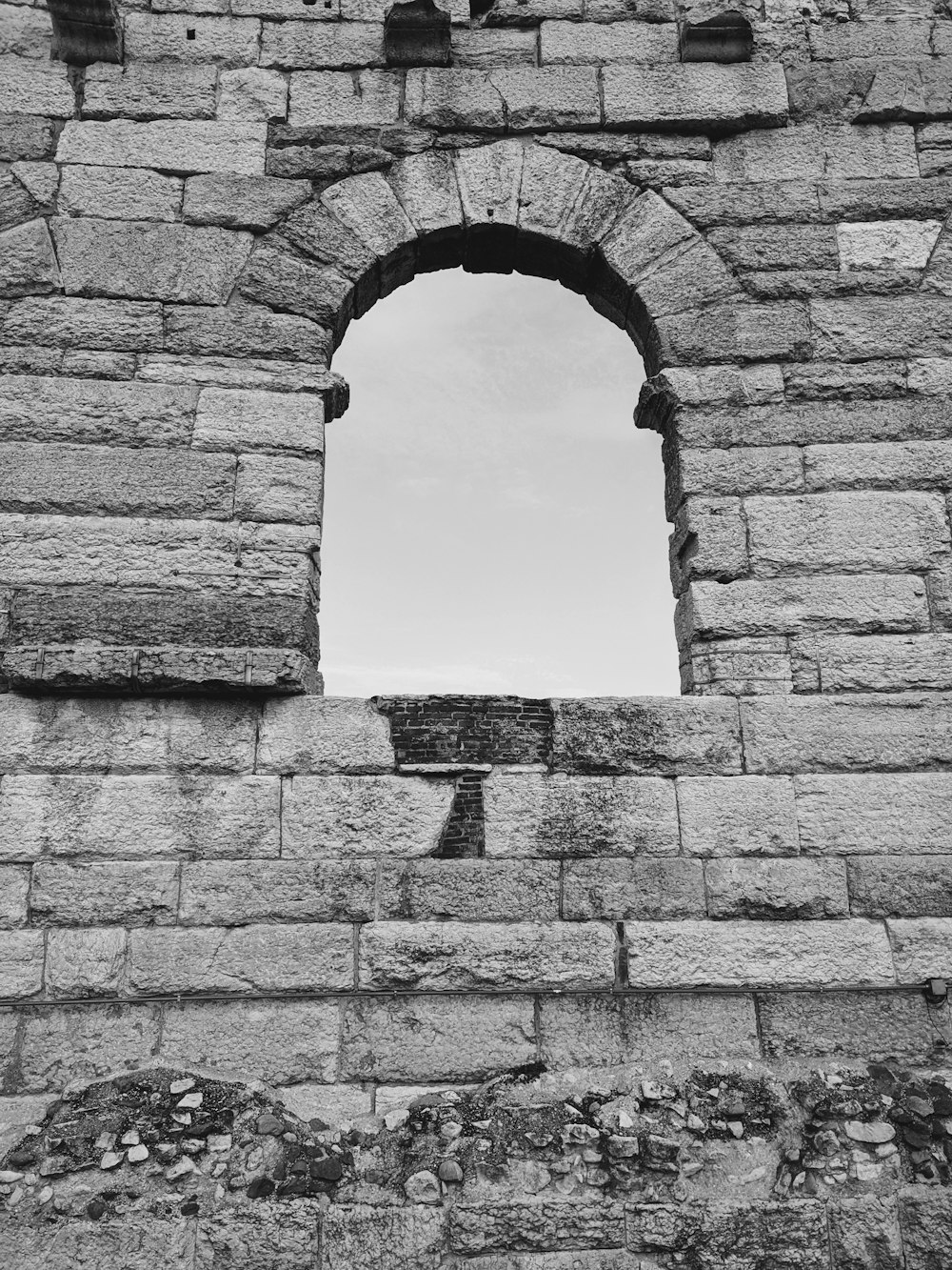 a black and white photo of a window in a stone wall