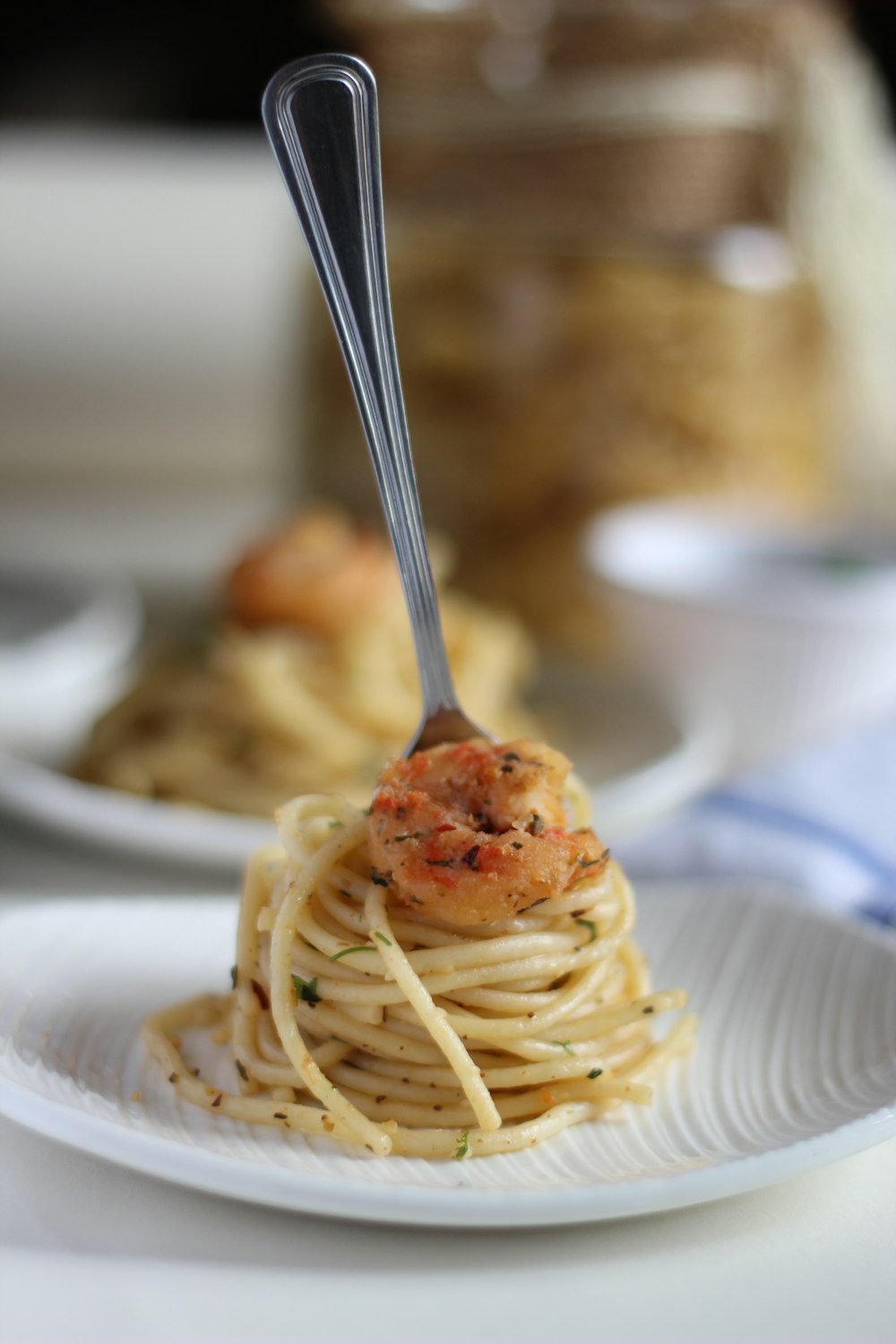 a white plate topped with spaghetti and shrimp