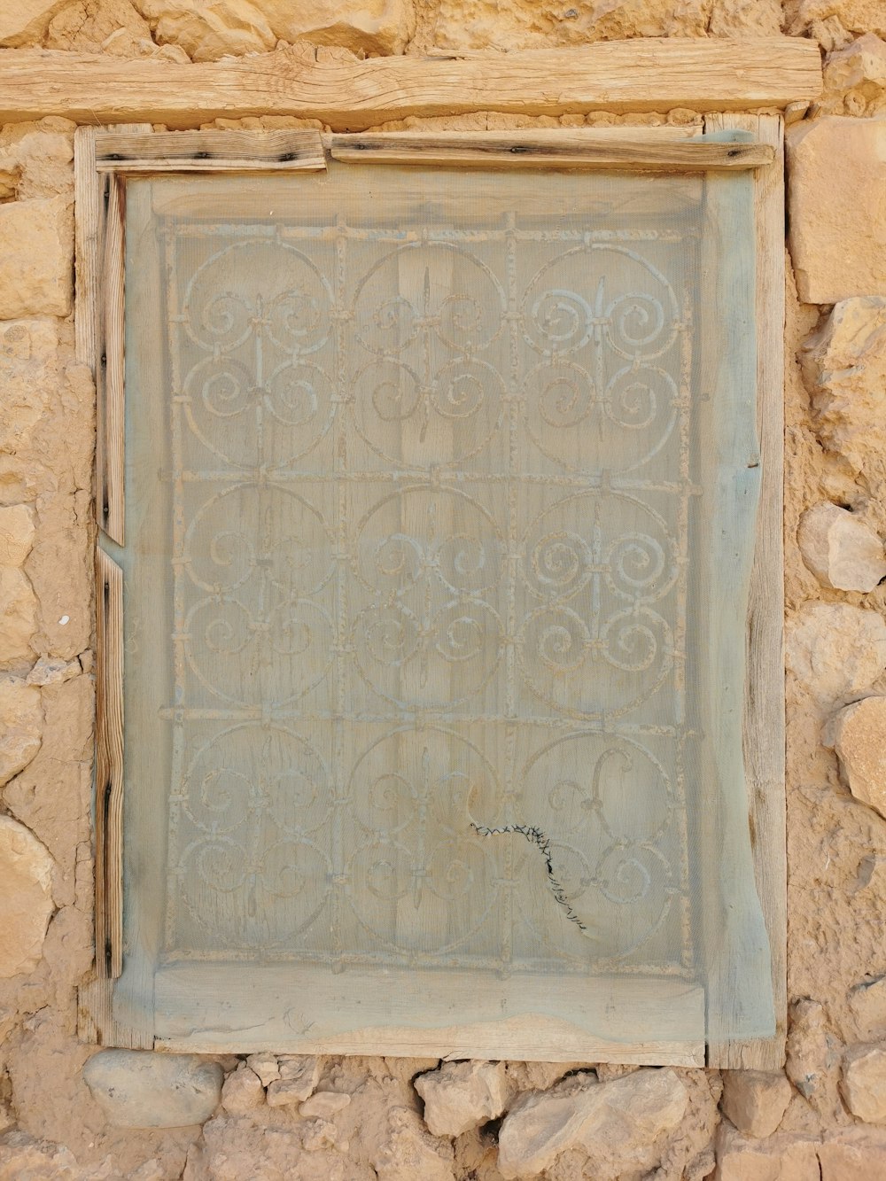 a window in a stone wall with a metal grate