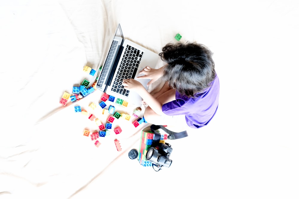 a person sitting on a bed using a laptop