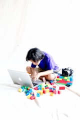 a young girl sitting on a bed using a laptop computer