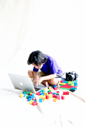 a young girl sitting on a bed using a laptop computer