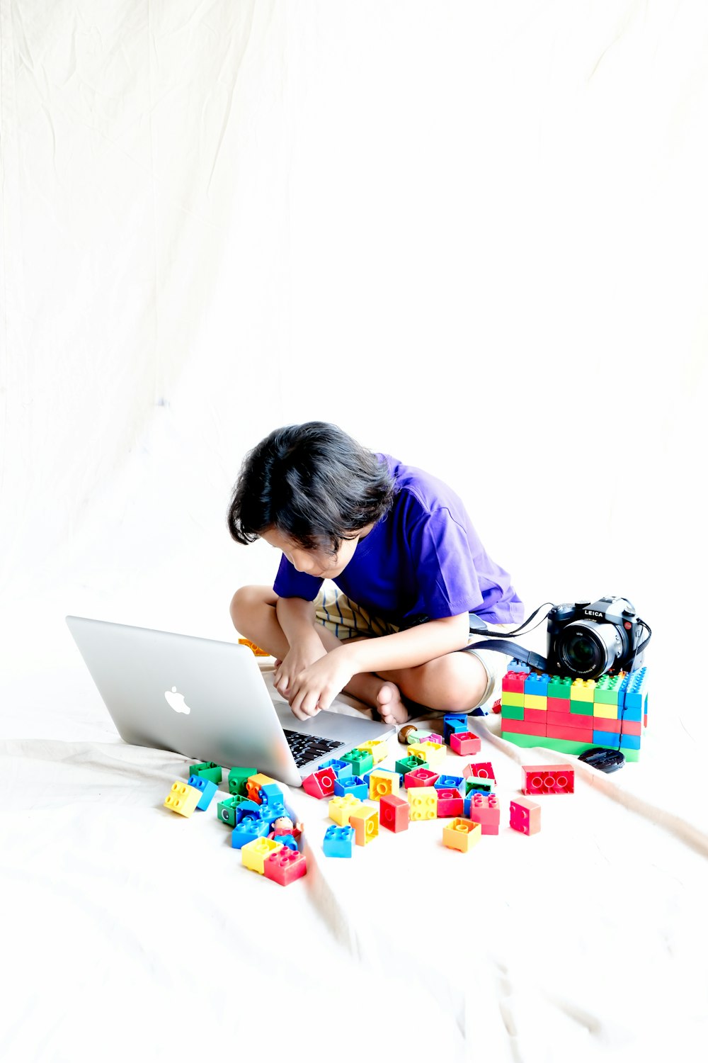 a young girl sitting on a bed using a laptop computer