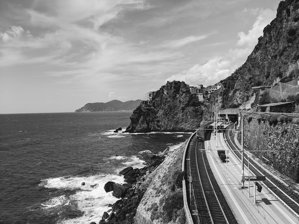 a black and white photo of a train on the tracks next to the ocean