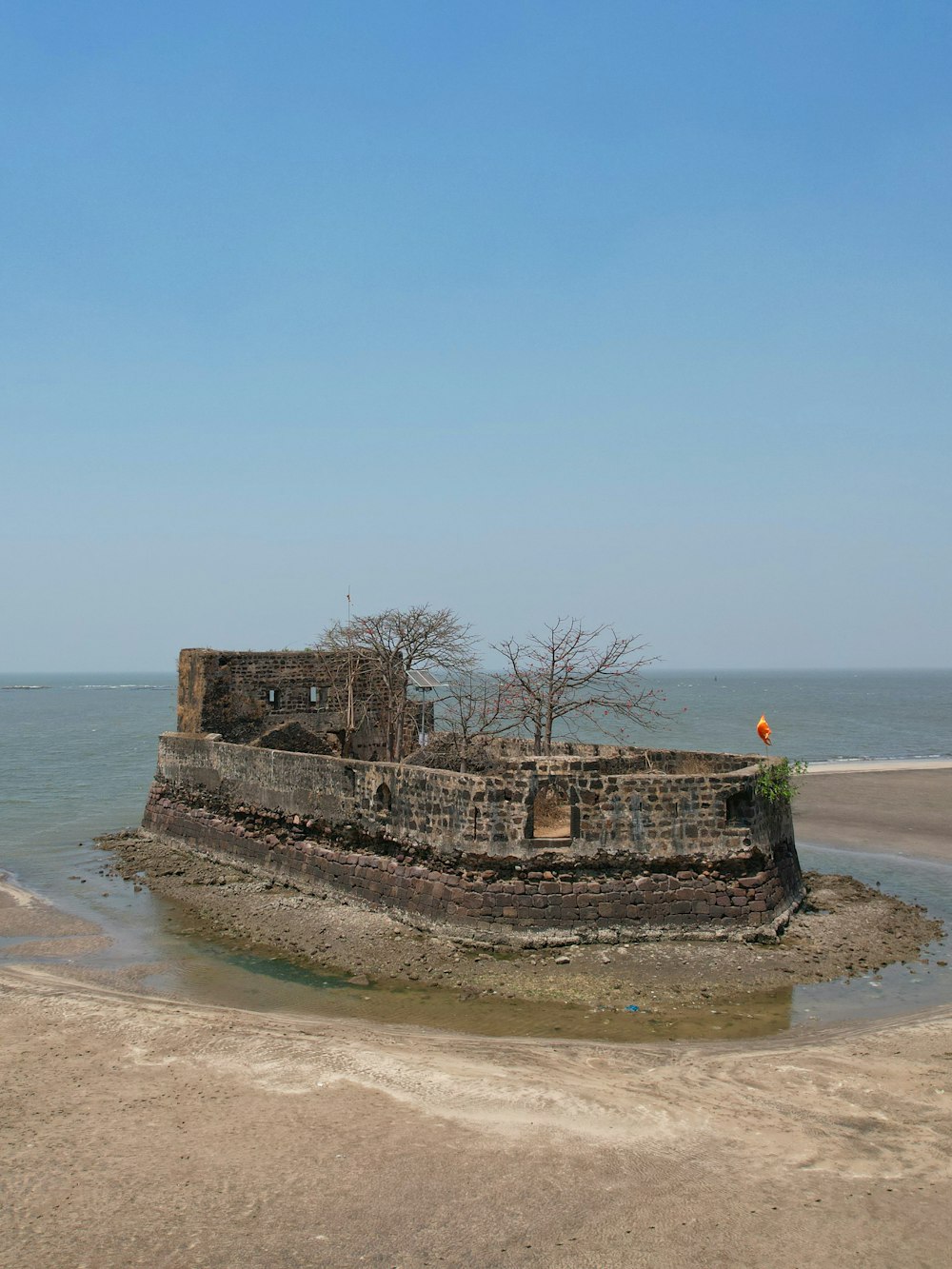 une vieille structure en brique assise au sommet d’une plage de sable