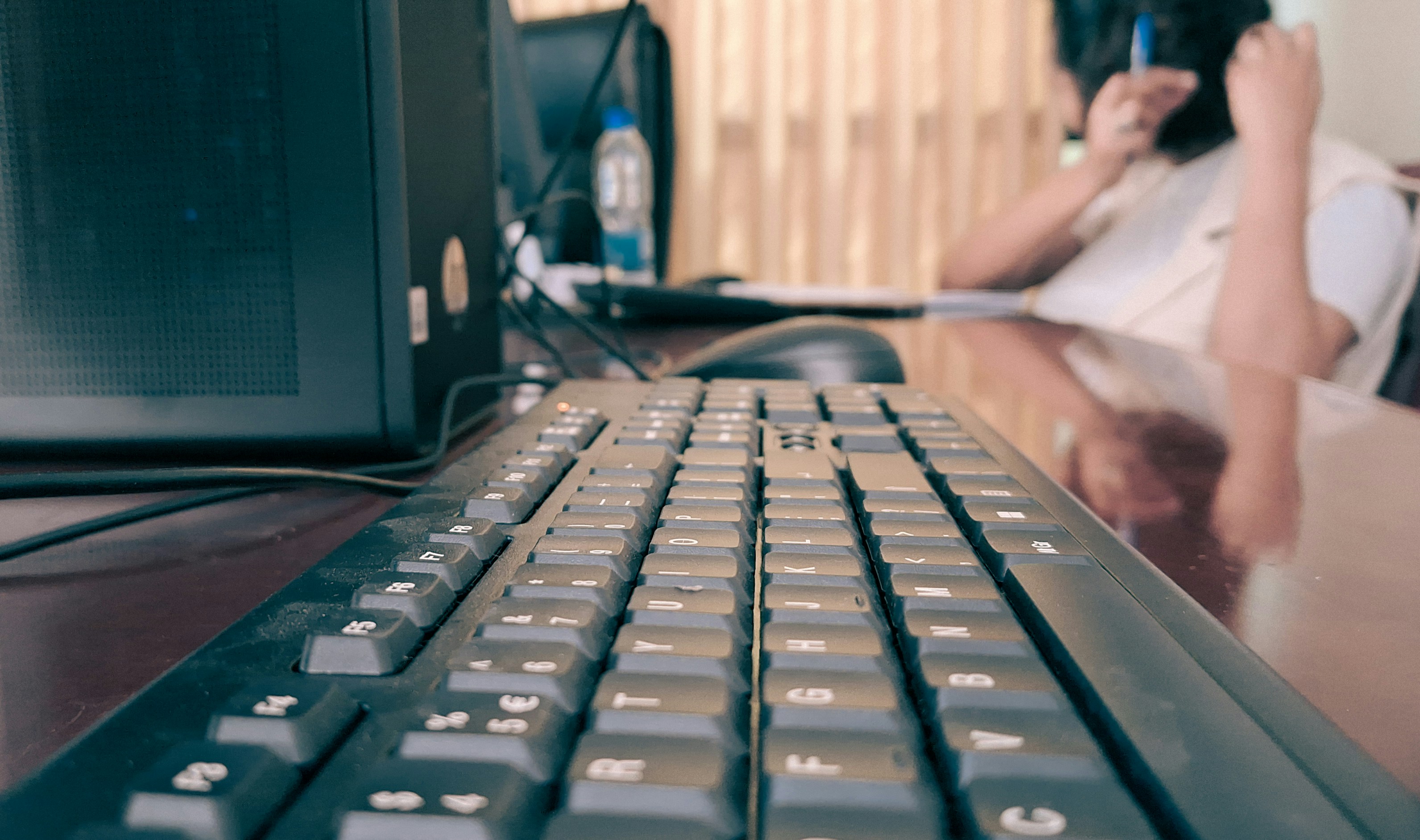 a woman sitting at a desk with a computer keyboard