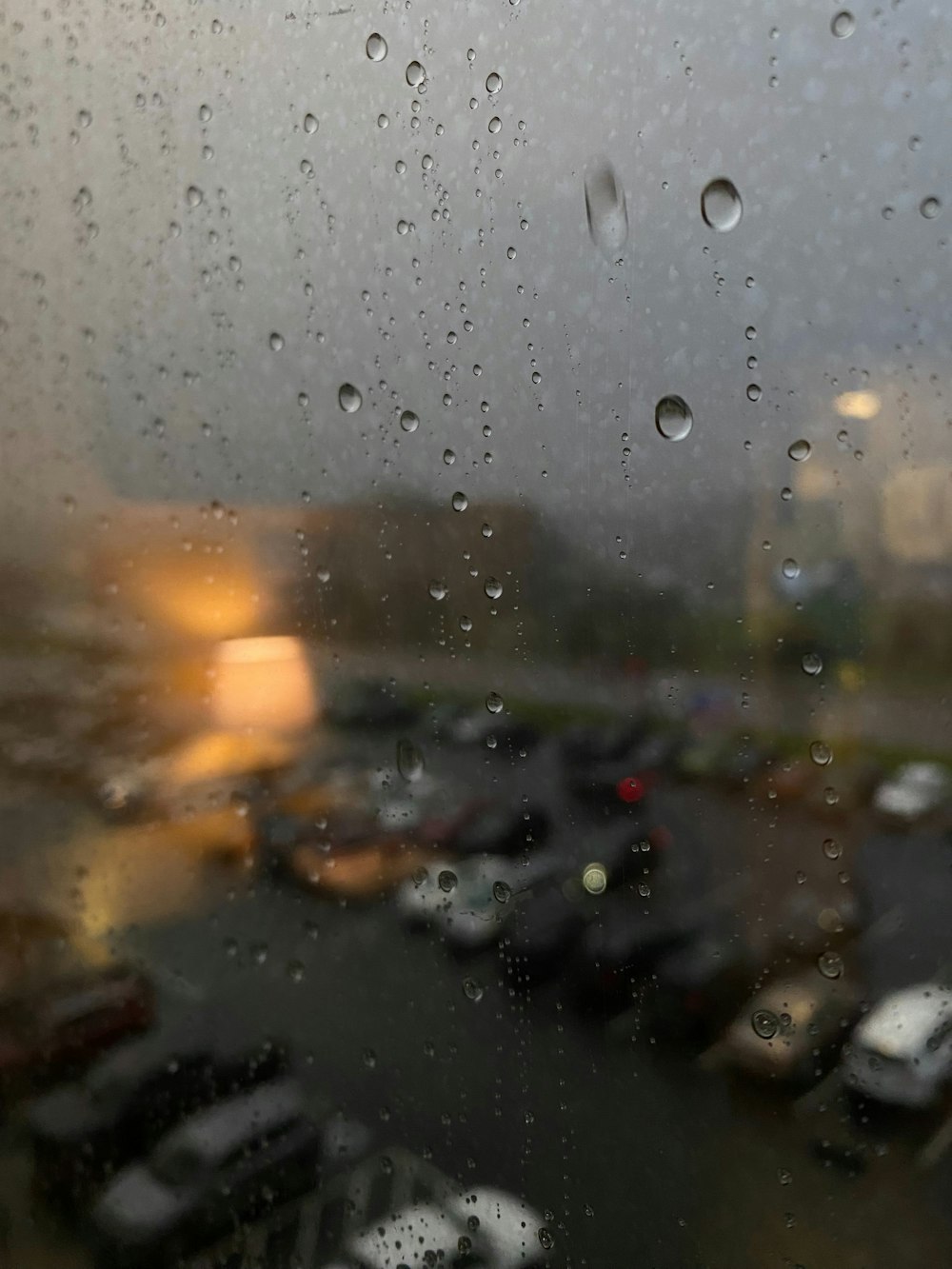 Una vista de un estacionamiento a través de una ventana cubierta por la lluvia