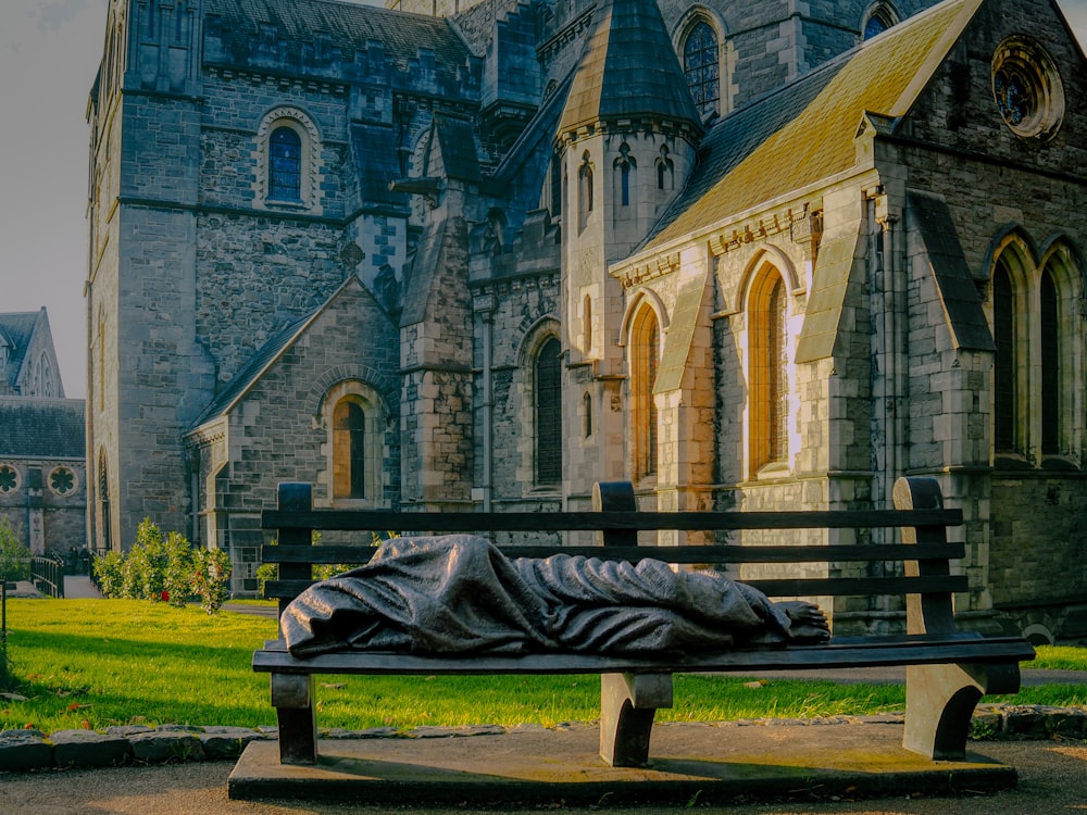 a statue of a person laying on a bench in front of a building