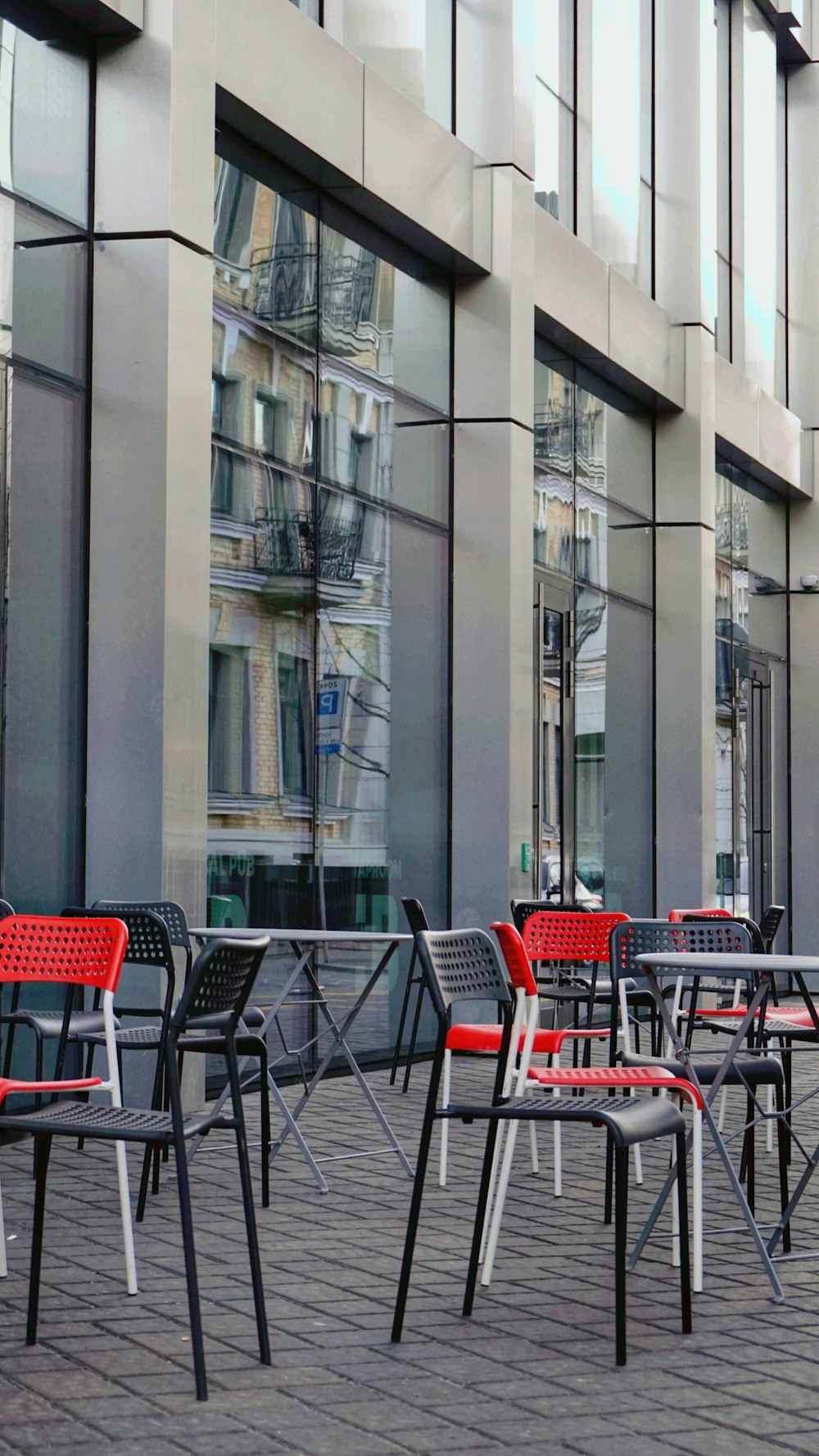 a row of red and black chairs sitting on top of a sidewalk