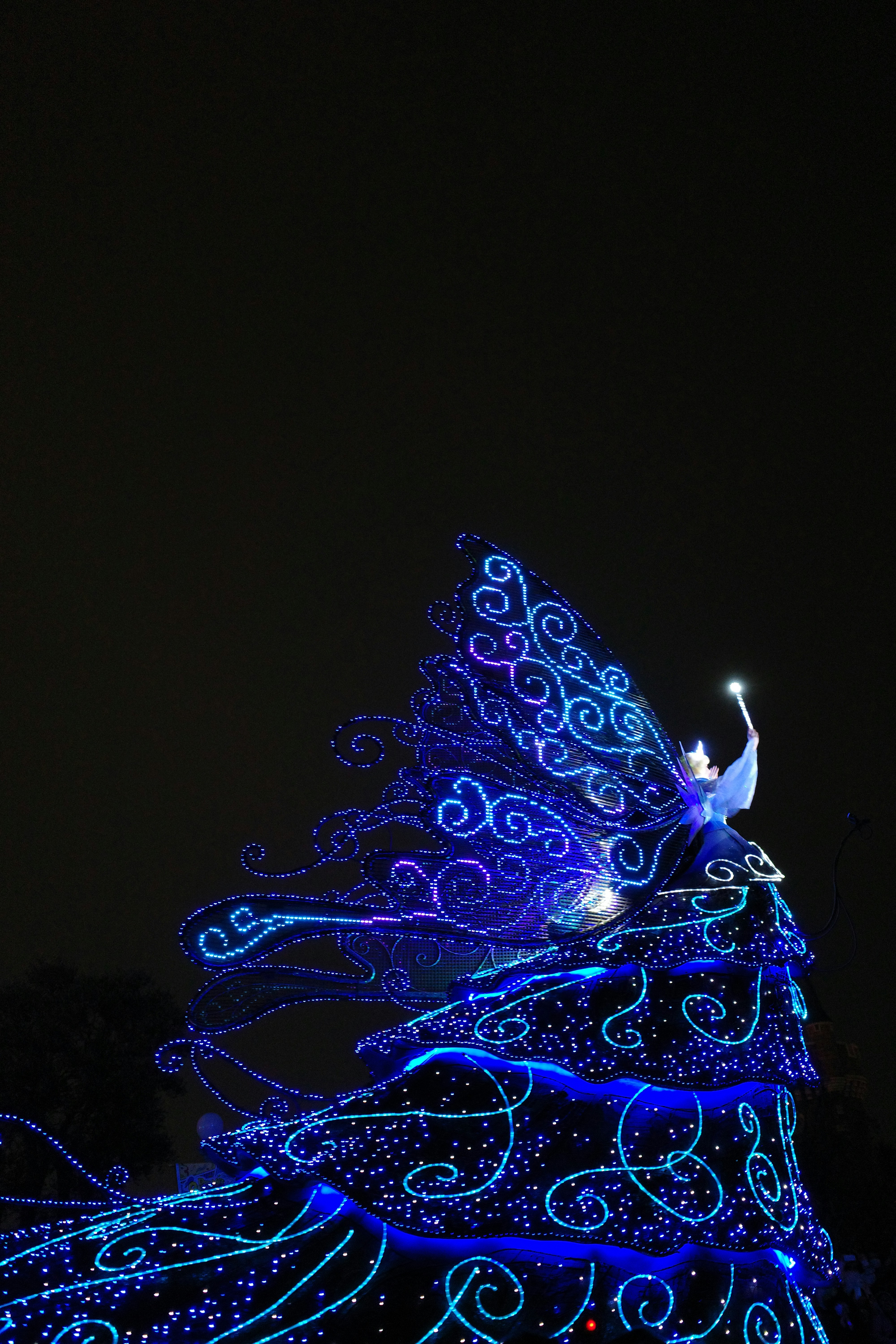 a lit up peacock on top of a tree