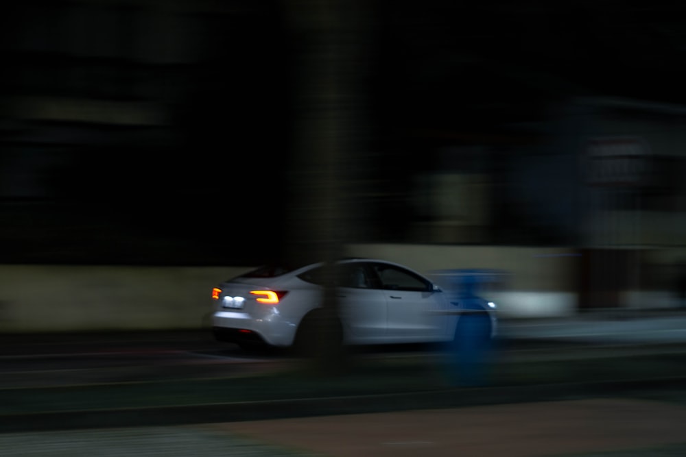 a white car driving down a street at night