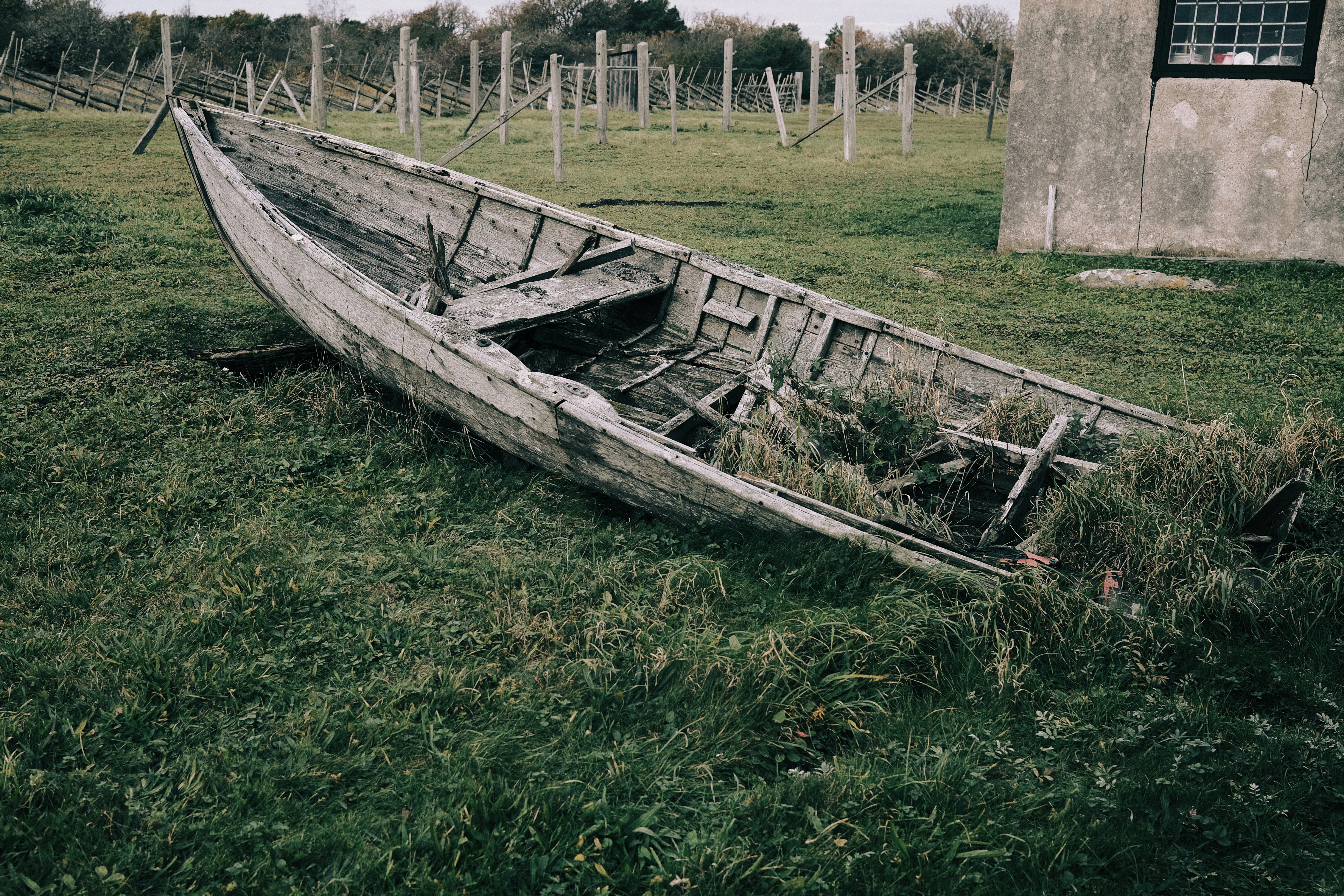 a wooden boat sitting on top of a lush green field